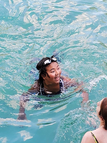 A Troop 19 looking up and smiling while treading water in a swimming pool.